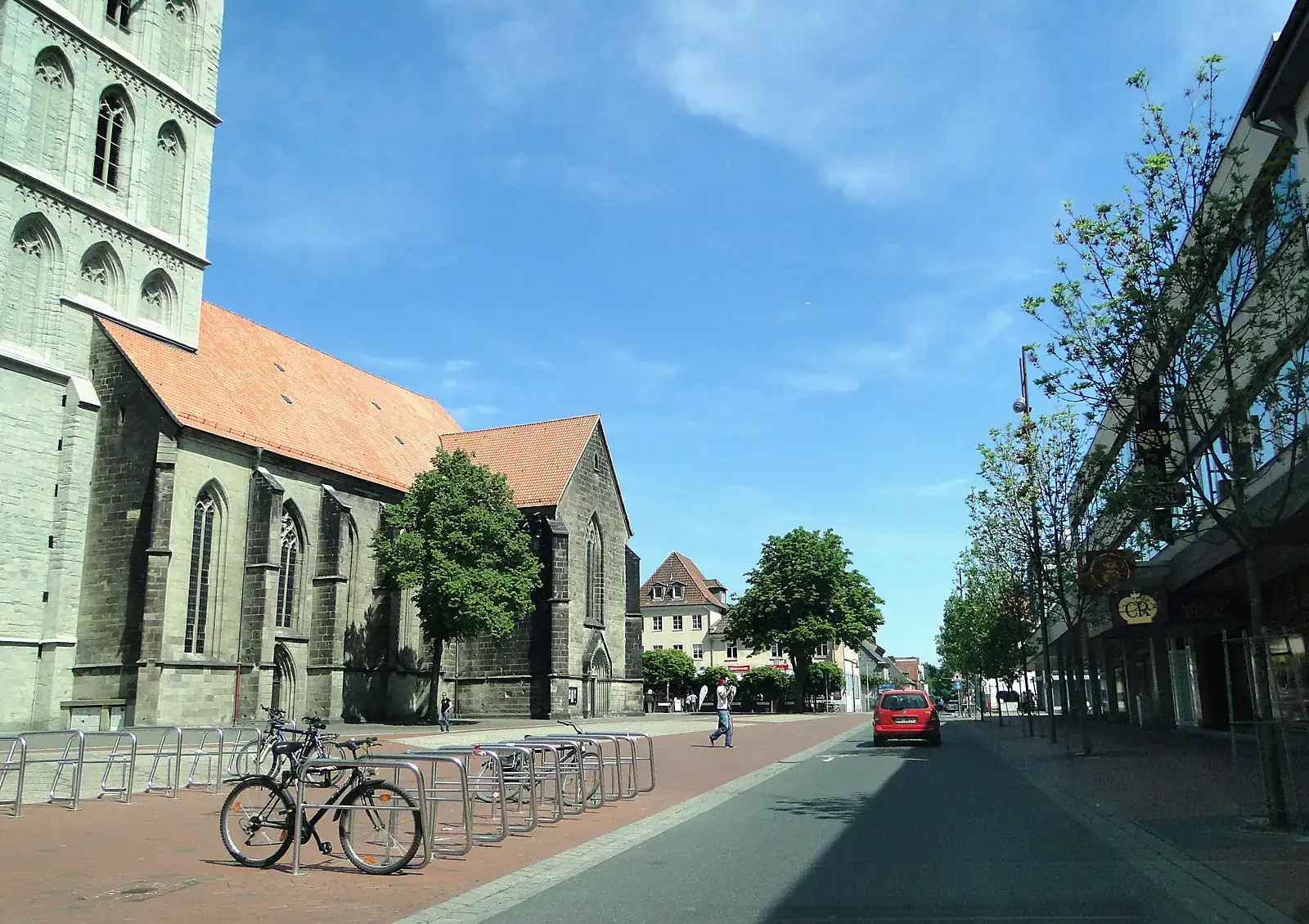 Pauluskirche aus grauem Naturstein am Marktplatz in Hamm, rechts Häuser und Bäume unter blauem Himmel