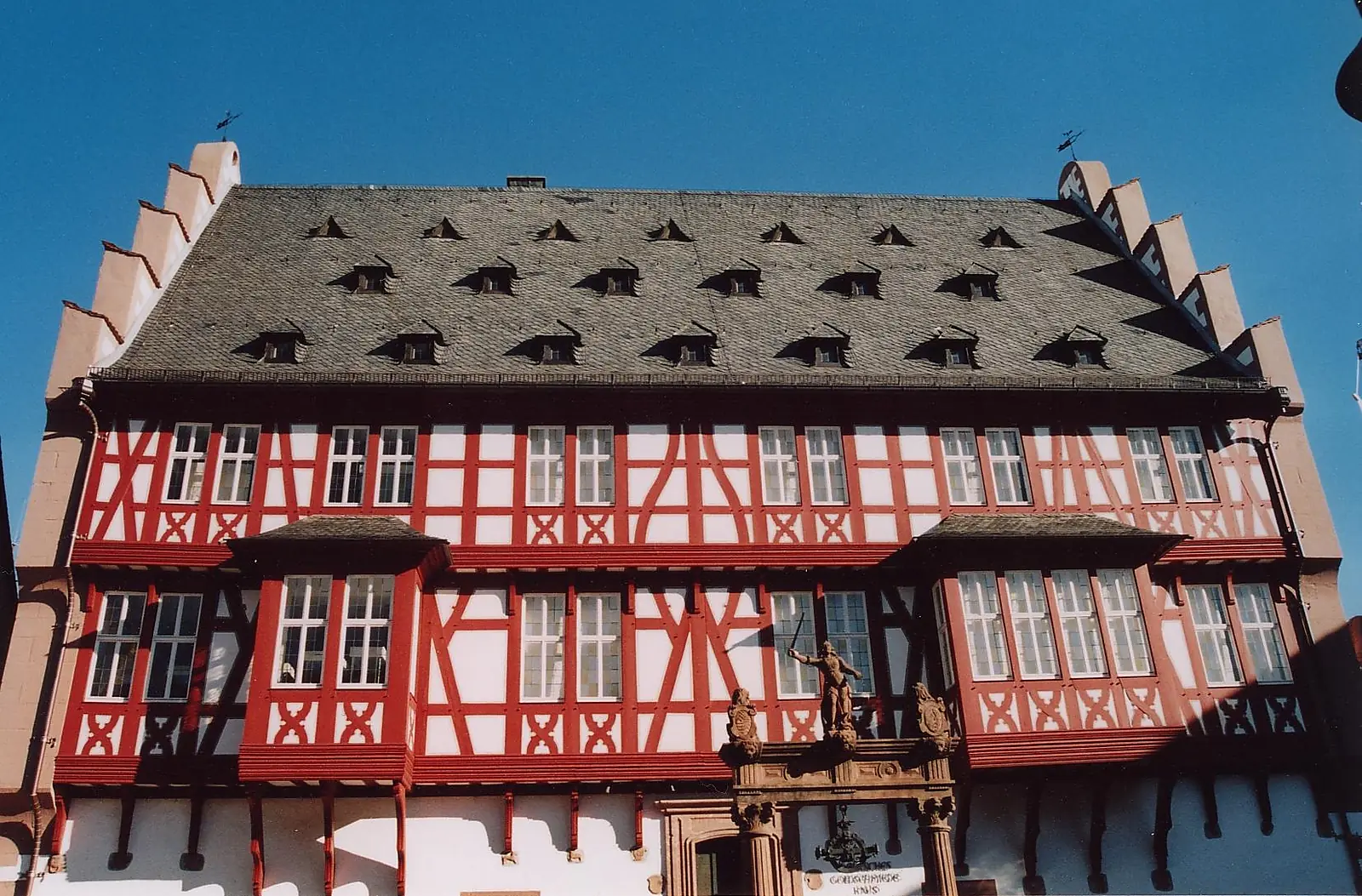 Das Deutsche Goldschmiedehaus in Hanau, ein Fachwerkbau mit roten Balken und dunklem Dach unter blauem Himmel