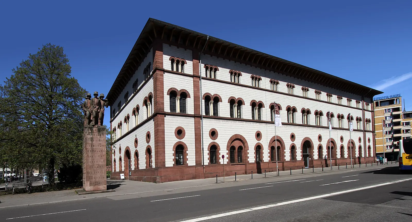 Die Fruchthalle in Kaiserslautern, ein langgestrecktes Gebäude mit rotem Sandstein, weißem Putz und Rundbogenfenstern