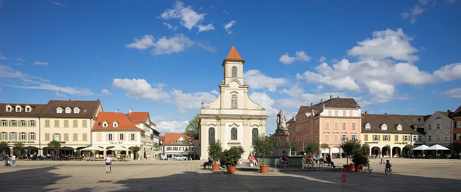 Marktplatz in Ludwigsburg mit Dreieinigkeitskirche und Arkadenhäusern unter blauem Himmel mit Wolken