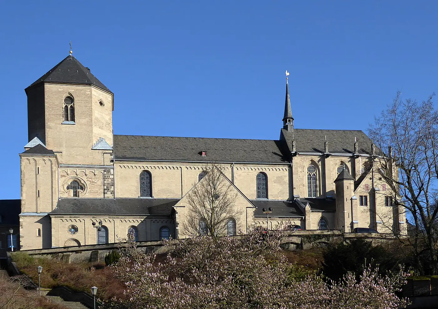 Münster St. Vitus in Mönchengladbach von der Seite, helle Sandsteinwände und achteckiger Turm vor blauem Himmel
