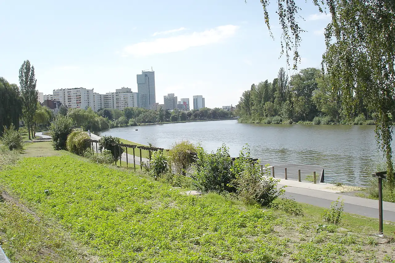 Der Main bei Offenbach mit Uferweg, Bäumen und der Hochhauskulisse der Stadt unter hellem Himmel