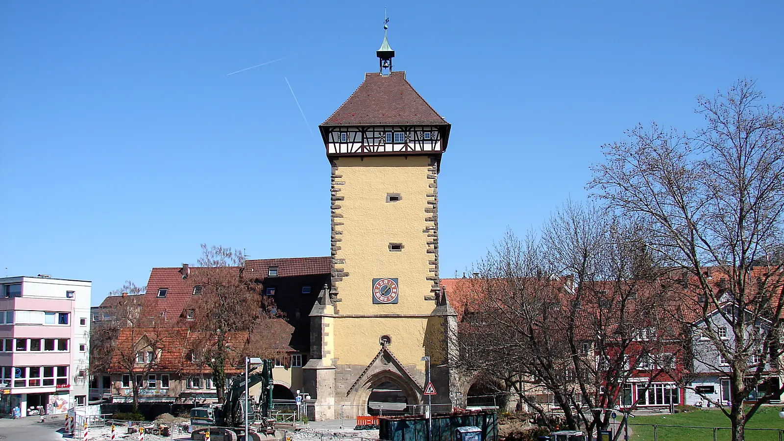 Das Tübinger Tor in Reutlingen, ein gelber Torturm mit Fachwerkgeschoss und Ziegeldach, davor kahle Bäume